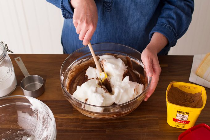 Person using a spatula to fold together chocolate and cream