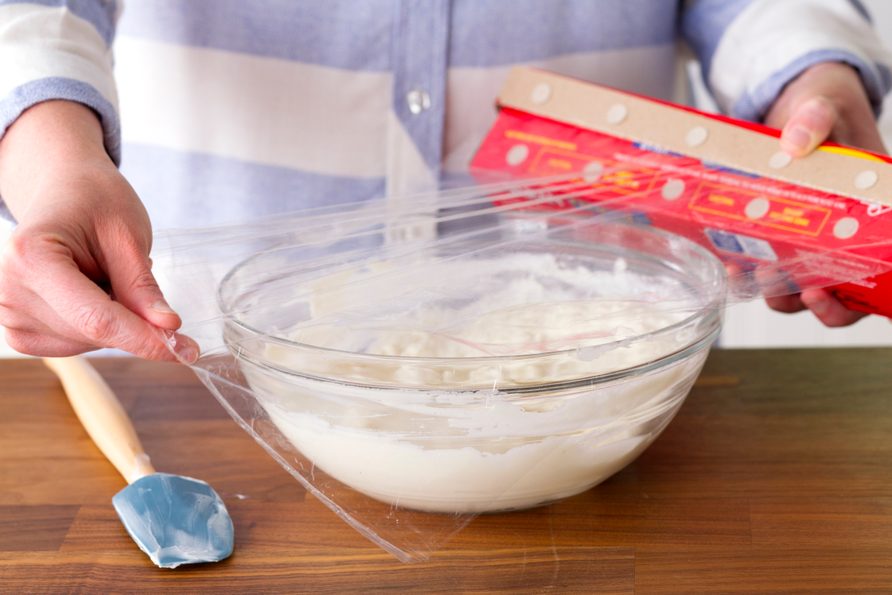 The gelatin mixture, now combined with the yogurt, being covered in plastic wrap