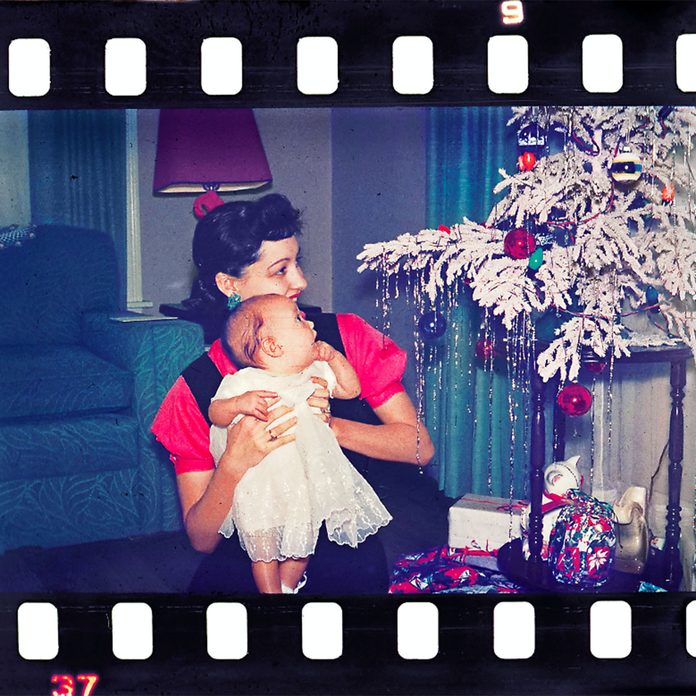 Mother holding up her baby to see the Christmas tree