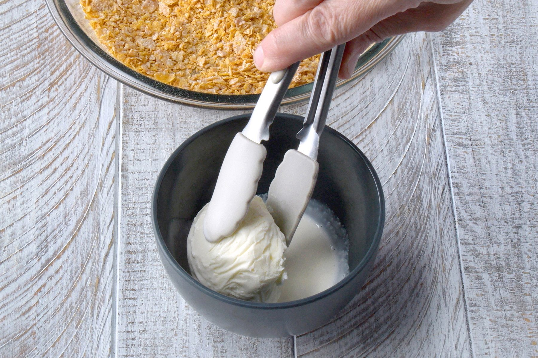 3/4th shot; white wooden background; Dipping ice cream balls into cream mixture