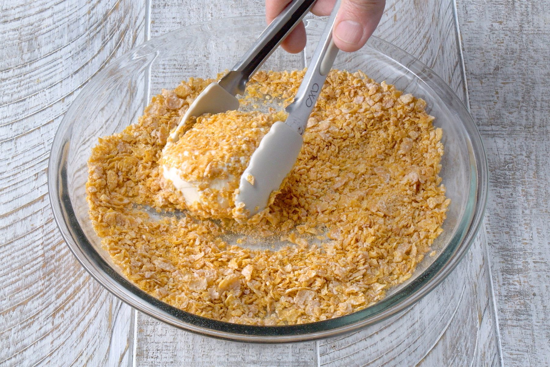 3/4th shot; white wooden background; rolling ice cream scoop in cornflake mixture