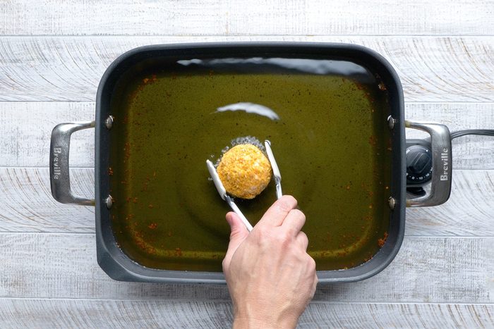 overhead shot; white wooden background; In an electric skillet or deep-fat fryer, Frying ice cream ball until golden