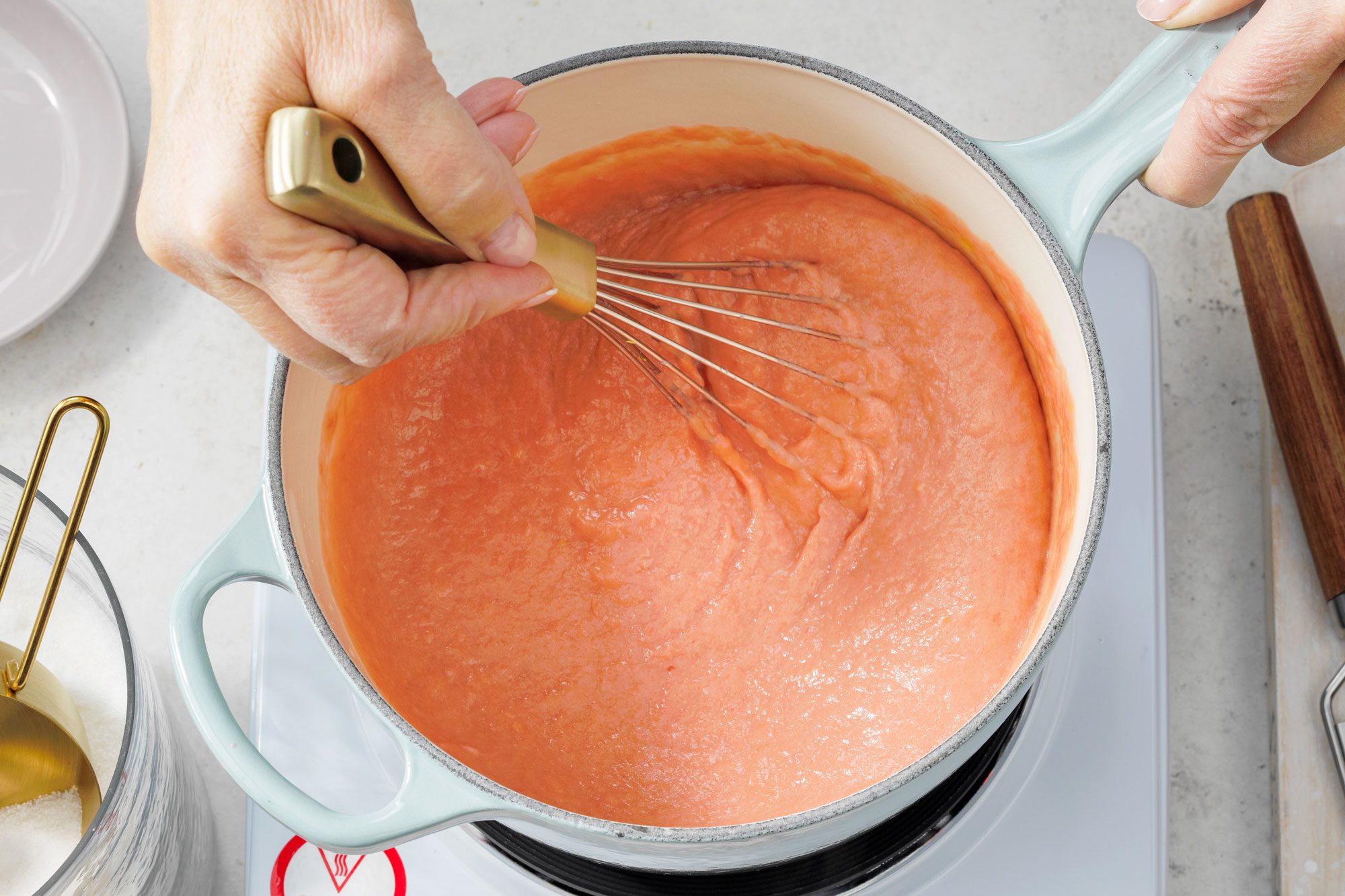 Mixing egg yolks, sugar, lemon juice and zest with rhubarb mixture in a small pan