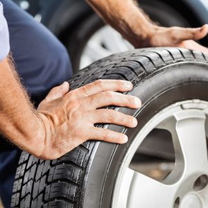 Mechanic Holding Car Tire At Garage.