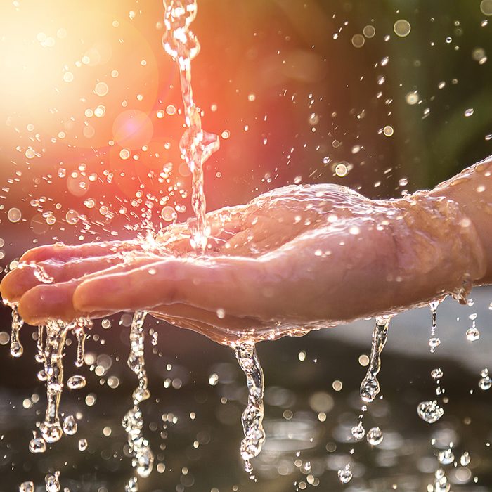 Hands with water splash, backlit by the evening sun.