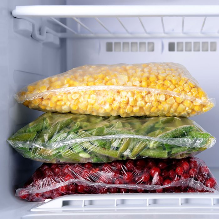 Frozen berries and vegetables in bags in freezer close up;