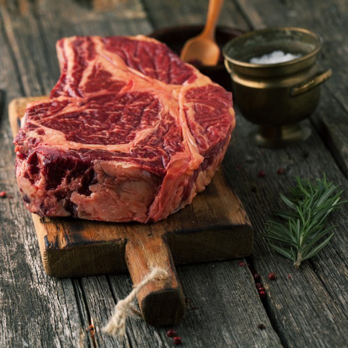 Raw fresh meat Ribeye Steak with pepper and salt on wooden background