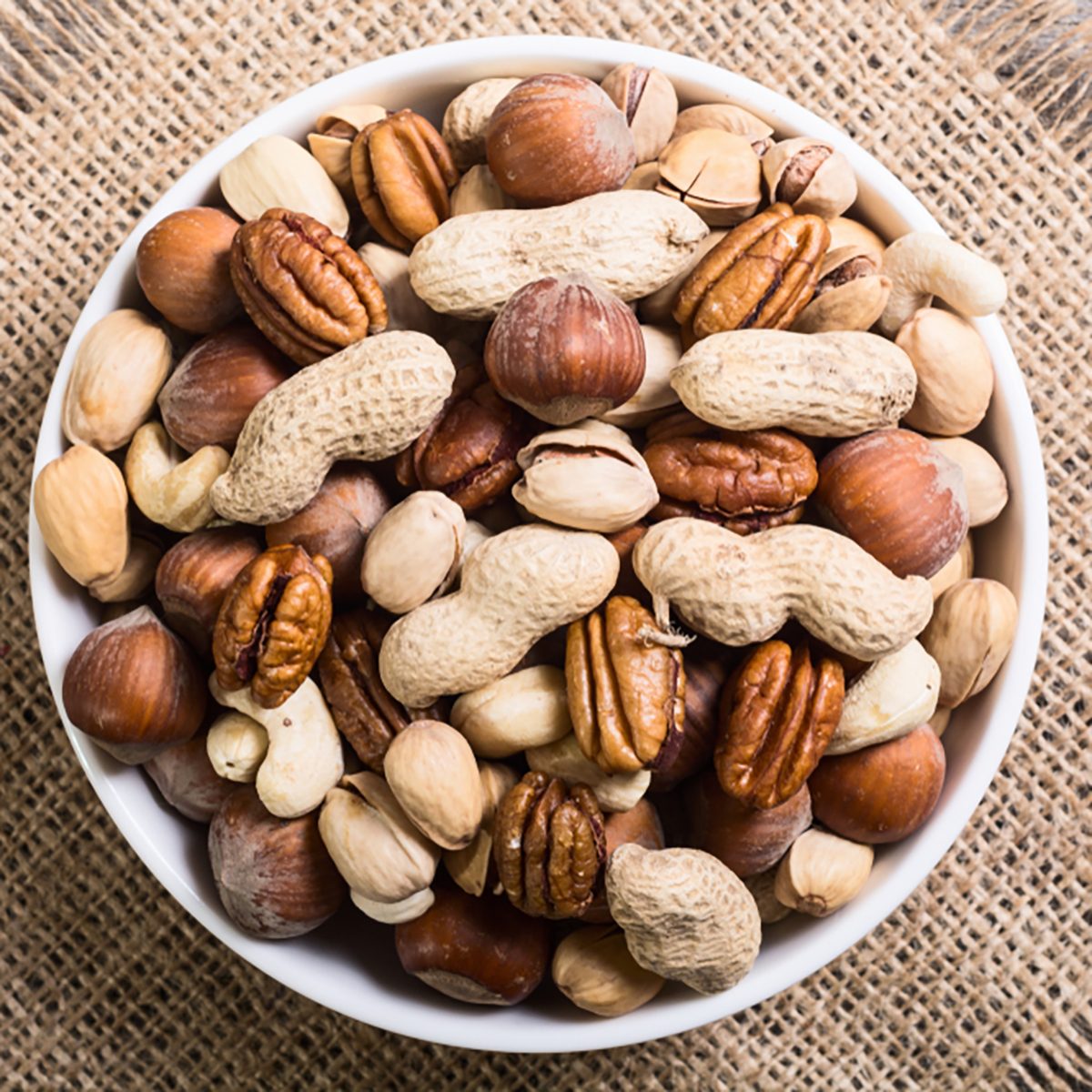 Mix of nuts in plate . pecan , hazelnut , pistachios , cashew and peanuts