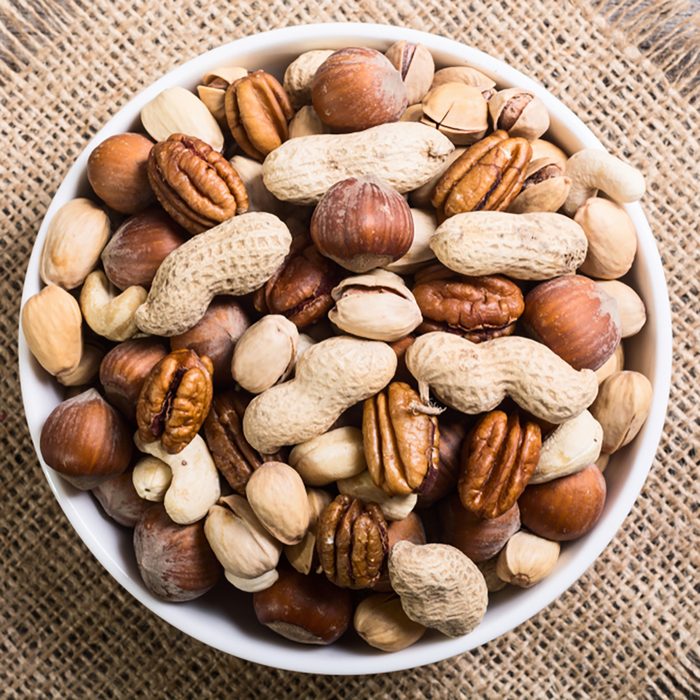 Mix of nuts in plate . pecan , hazelnut , pistachios , cashew and peanuts