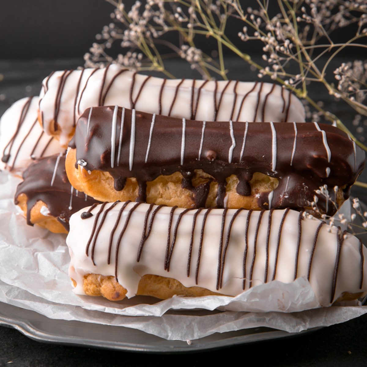 Assorted eclairs or profiteroles with black chocolate and white chocolate with custard inside on a metal plate on a dark background. Traditional French dessert. Empty space for design text template; Shutterstock ID 739322287; Job (TFH, TOH, RD, BNB, CWM, CM): Taste of Home