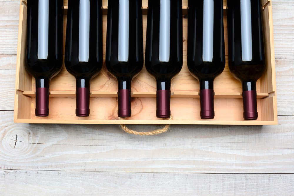 Wine crate with six bottles without labels. Horizontal format with copy space, on a white wood table shot from a high angle.