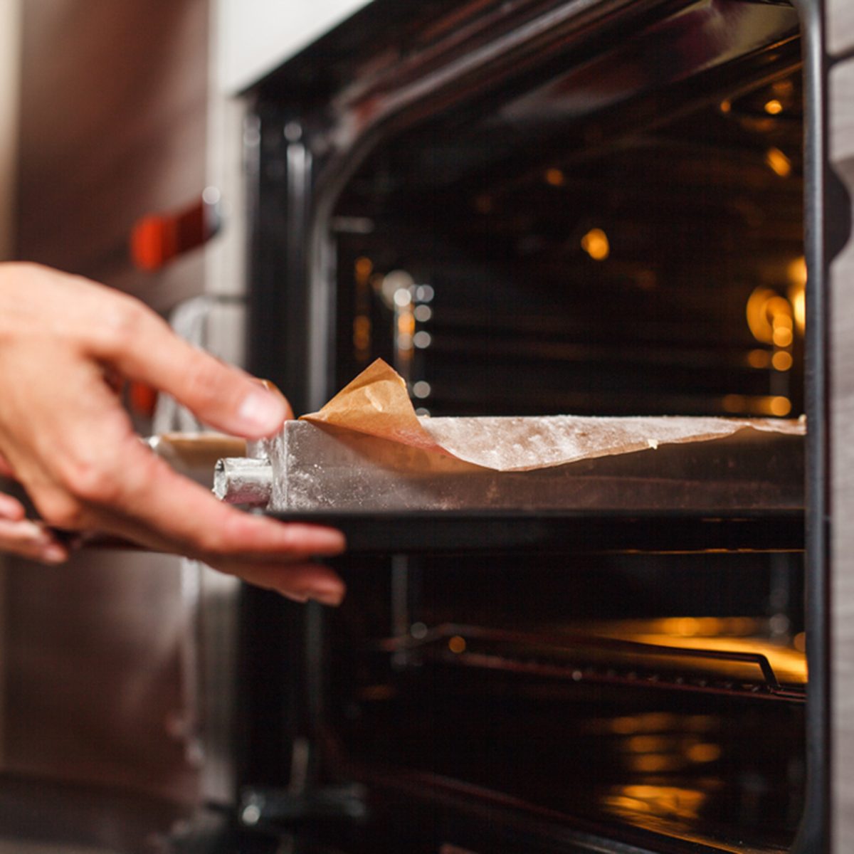 Woman cooking in the kitchen, puts cakes in the oven; Shutterstock ID 580824481