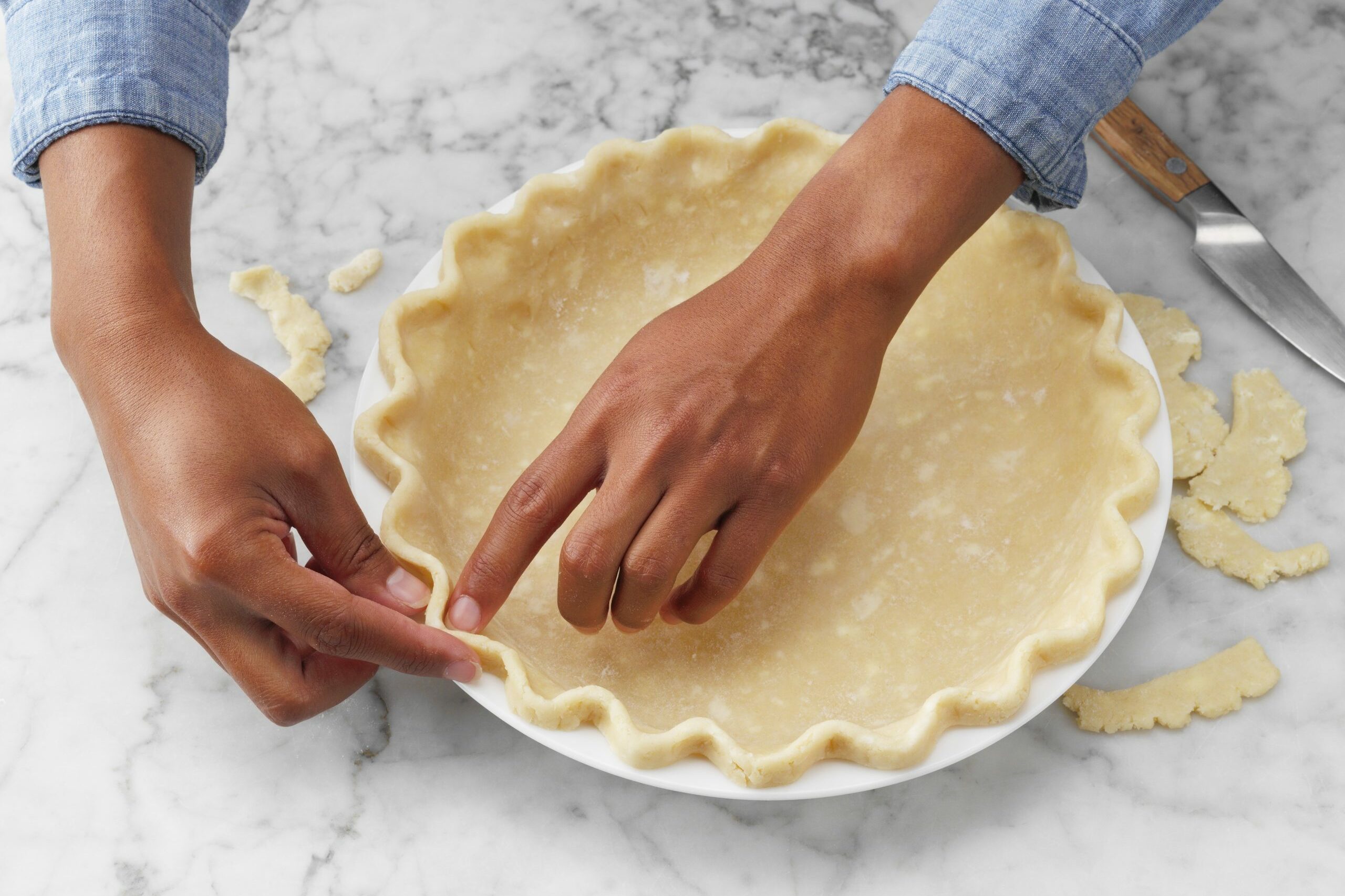 A female is giving shape to the corner of the pie dough