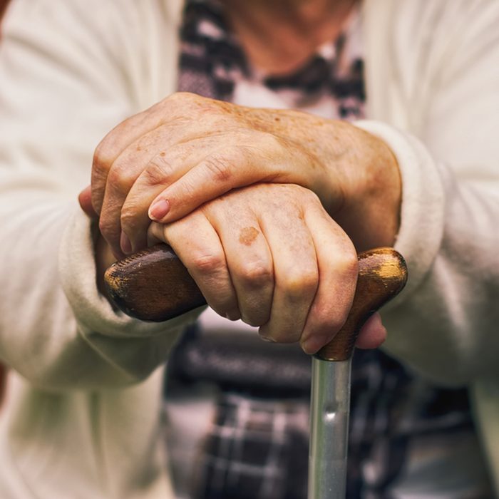 Senior woman sitting outside on a wooden bench and rests.