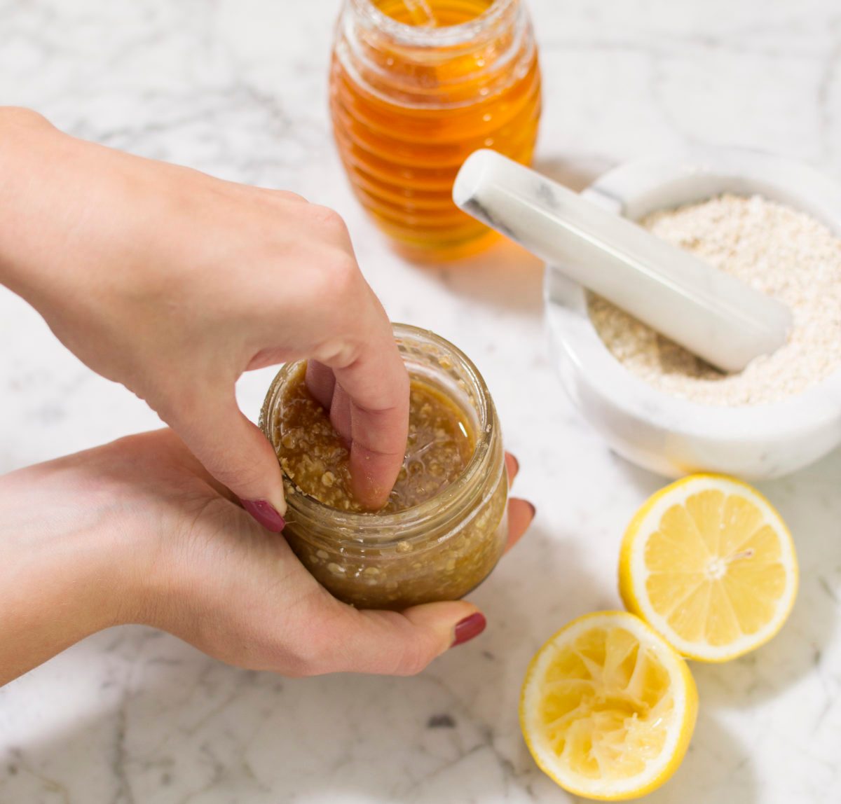 Hands scooping honey hand scrub out of a jar.
