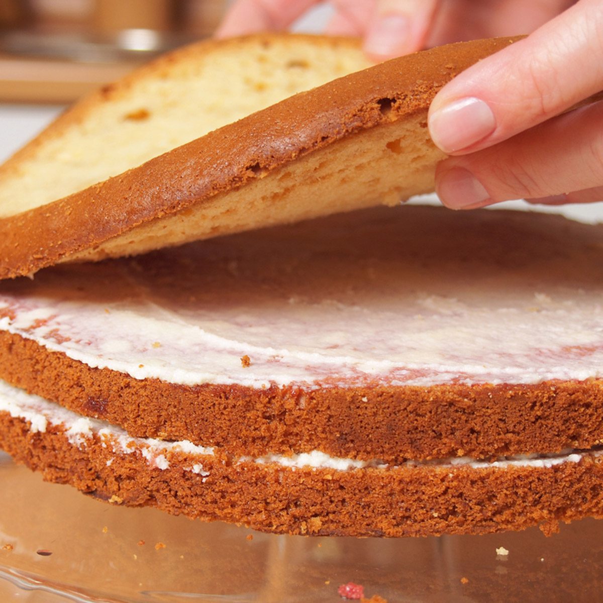 Stacking cake layers. Making torte with buttercream filling and grated chocolate topping.