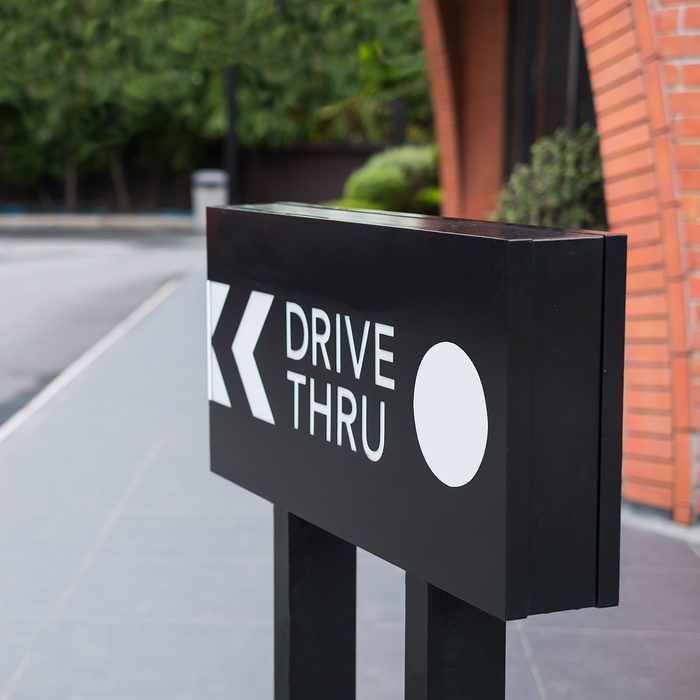 Drive thru sign with shop and road background.