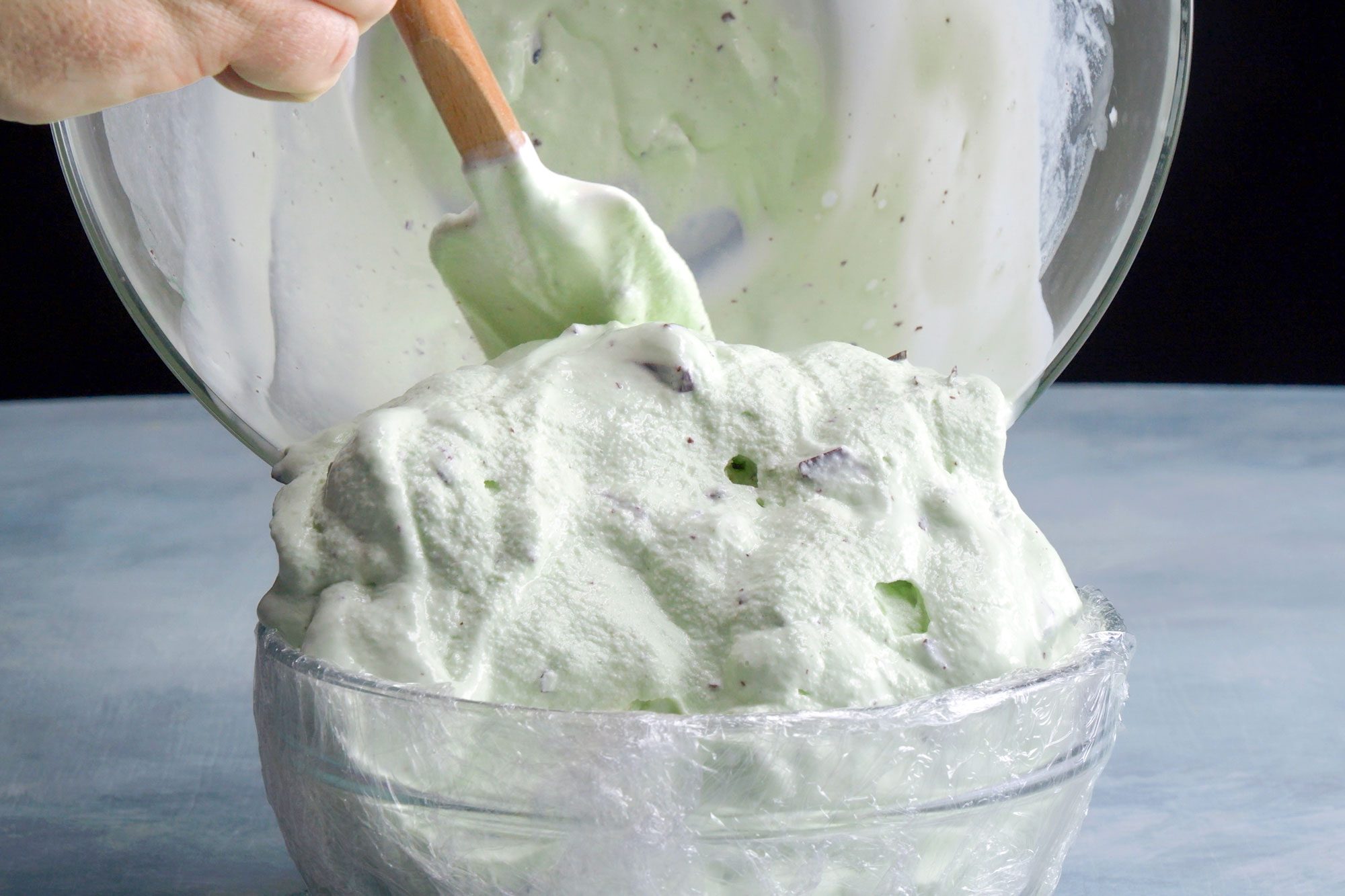 adding ice cream into the mold, a bowl lined with plastic wrap