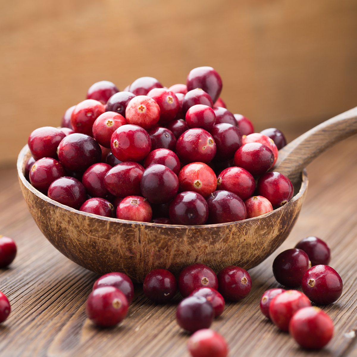Cranberries in wooden bowl on wooden background.