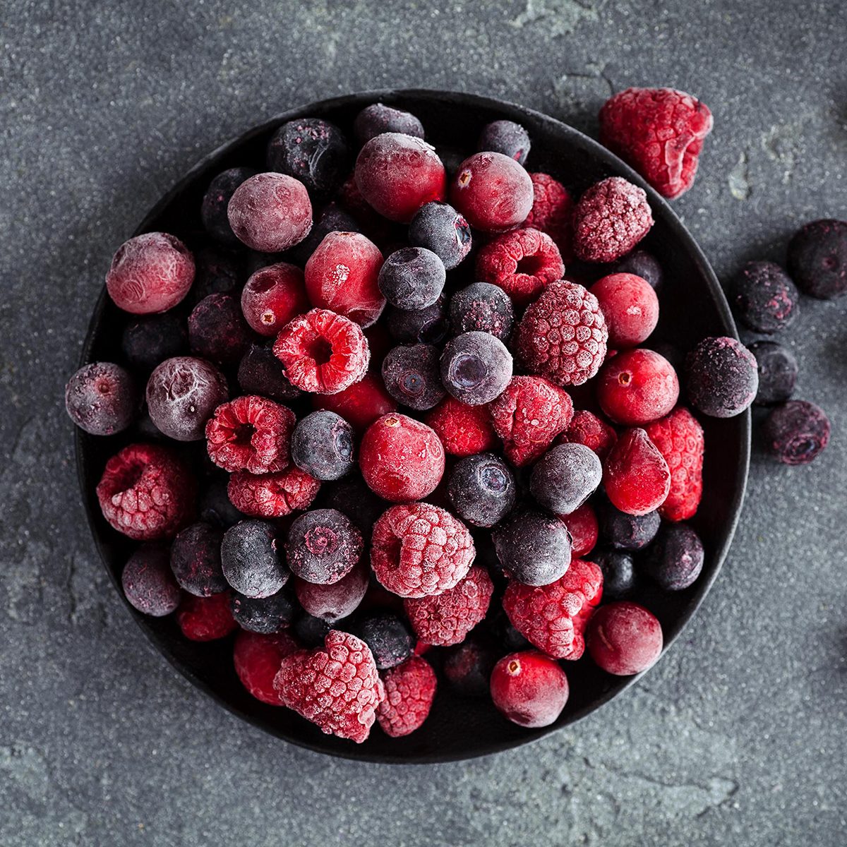 Frozen raspberry, blueberry, cranberry on black background.