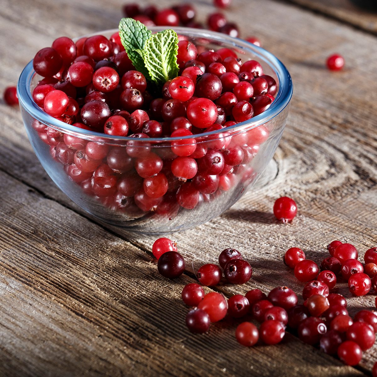 raw fresh cranberries in a plate on a wooden table.