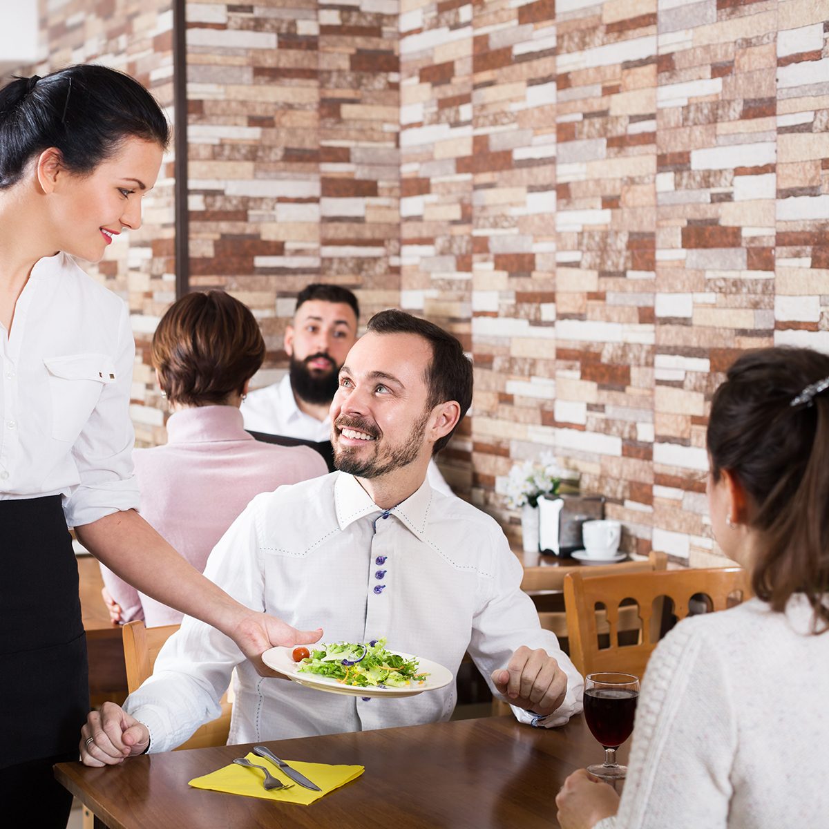 Positive waitress taking table order and smiling at the tavern