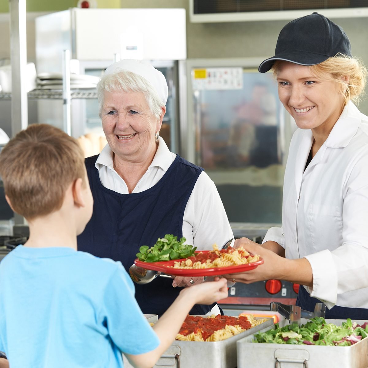 Pupils In School Cafeteria Being Served Lunch By Dinner Ladies