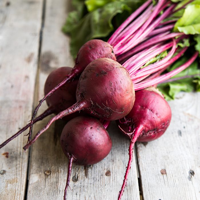 Red Beetroot with herbage green leaves on rustic background.