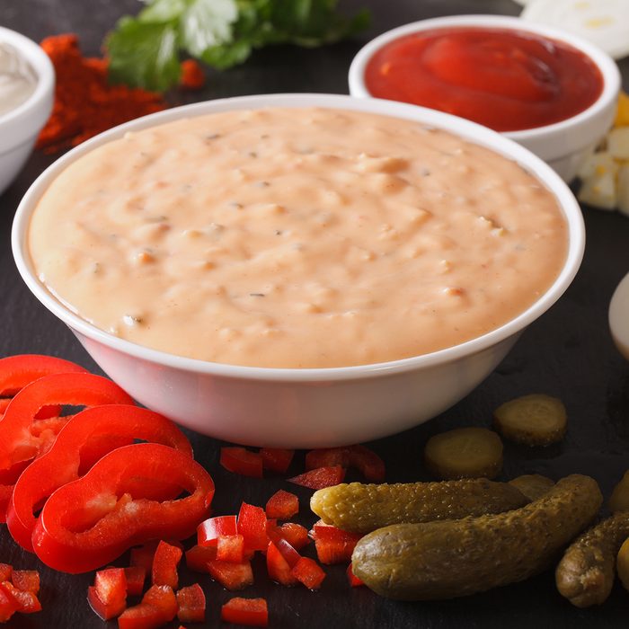 Dressing thousand islands surrounded by ingredients on a table close-up.