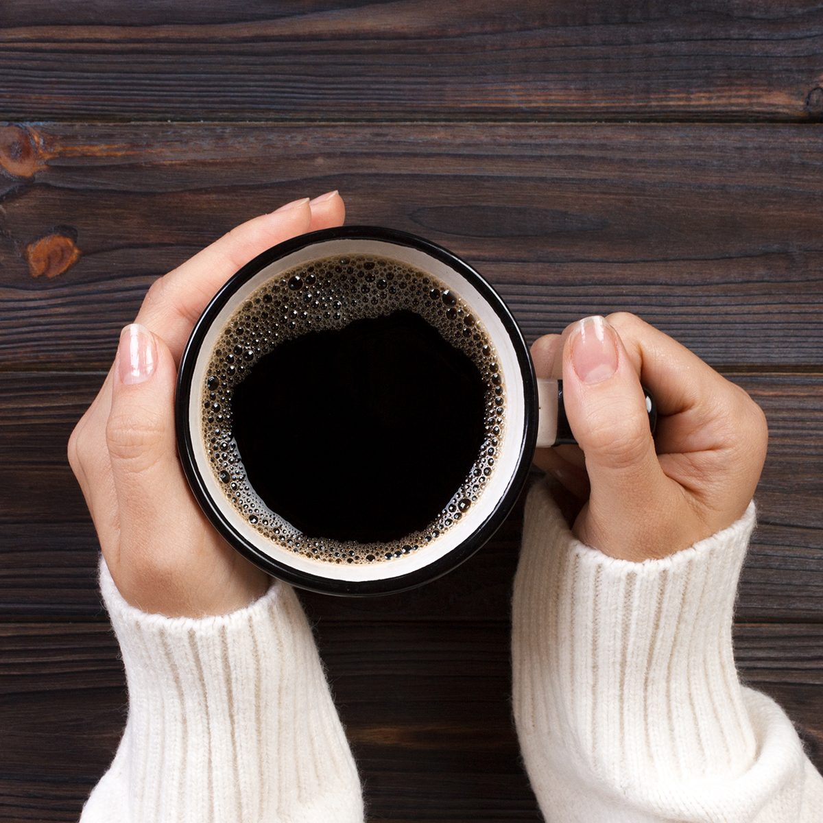 Directly Above Shot Of Woman Hands Holding Black Coffee In Cup On Table