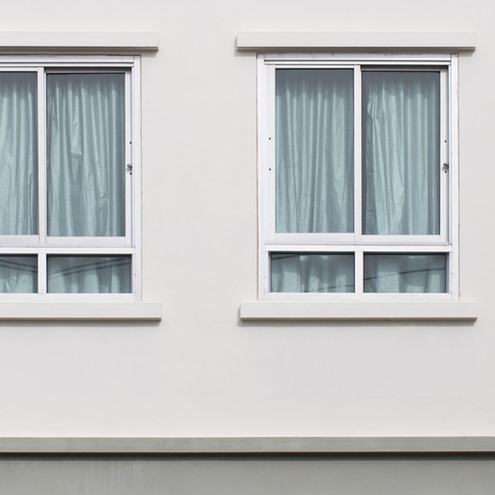 Two modern windows with uv protection curtain on white wall, outdoor view