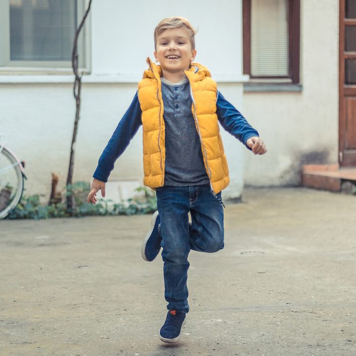 Happy kid having fun and jumping on one leg outdoors.