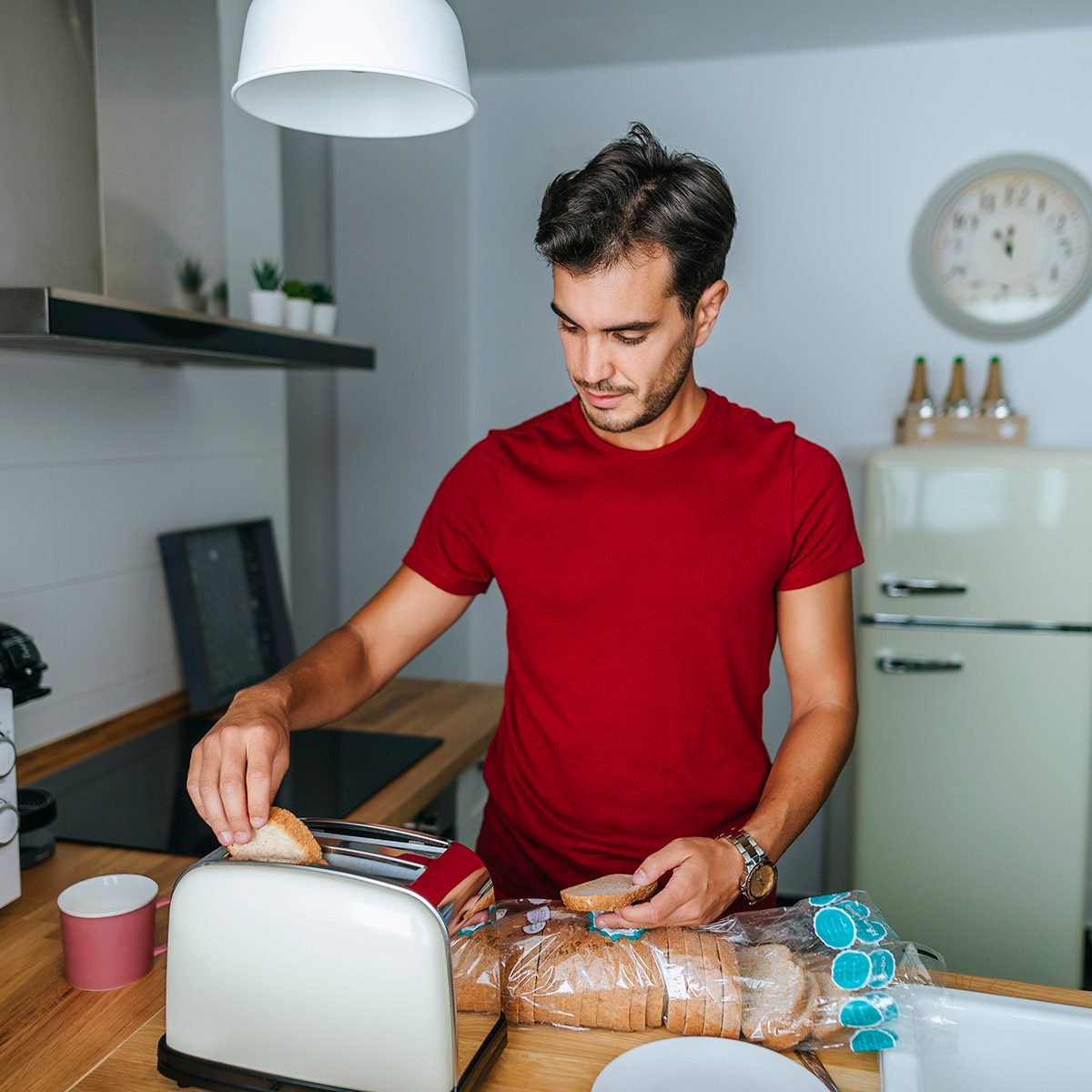 Man toasting bread with toaster in the kitchen