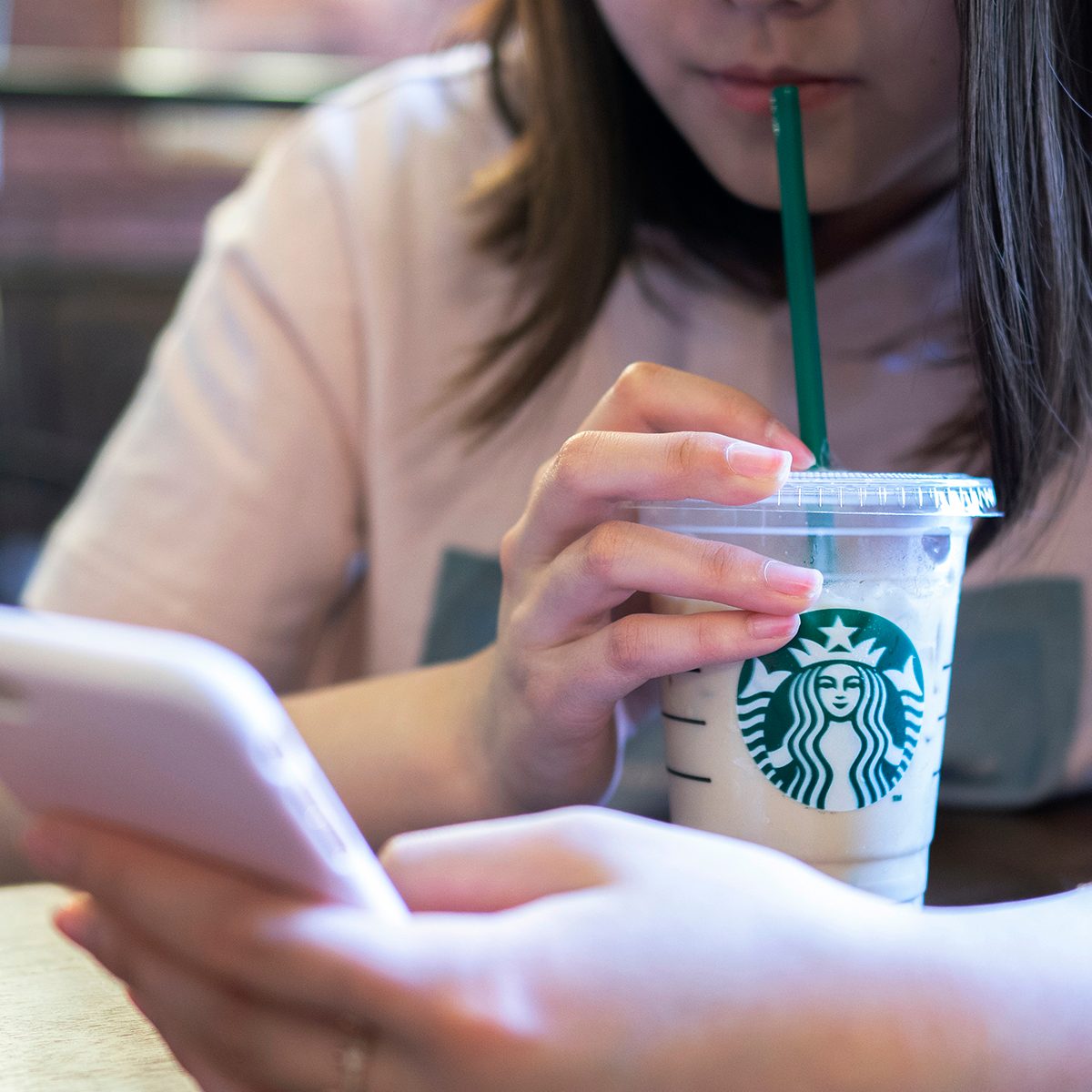 A Girl Is Drinking Ice Coffee In A Starbucks Coffee Shop.