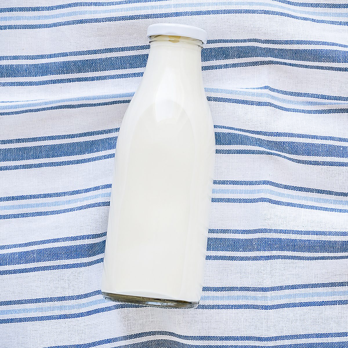 On a striped linen towel is a glass bottle of fresh milk. The concept of healthy organic, farm food. The view from the top. Copy space for text