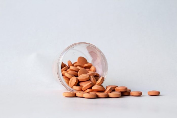 bottle of pills on a gray background with pills spilling out