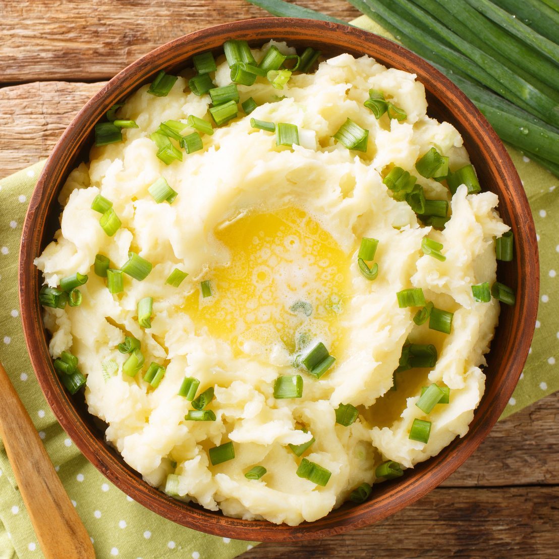 Irish Champ is a simple food made of potatoes, milk, green onions, butter close up in the bowl. Horizontal top view