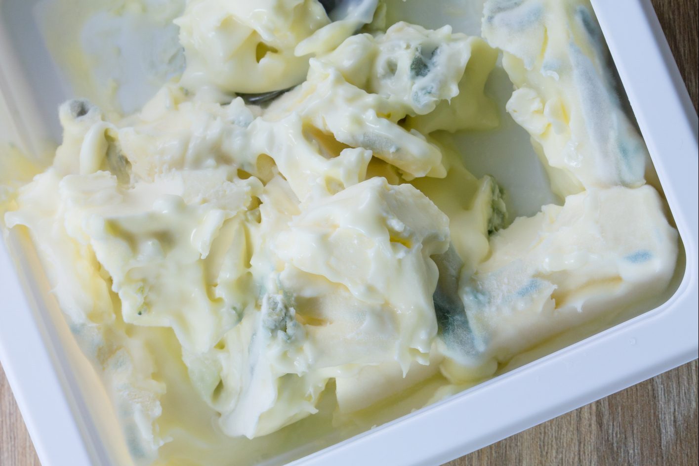 Mold, bacteria in a cream cheese on wood table background, Mold on cheese box background.