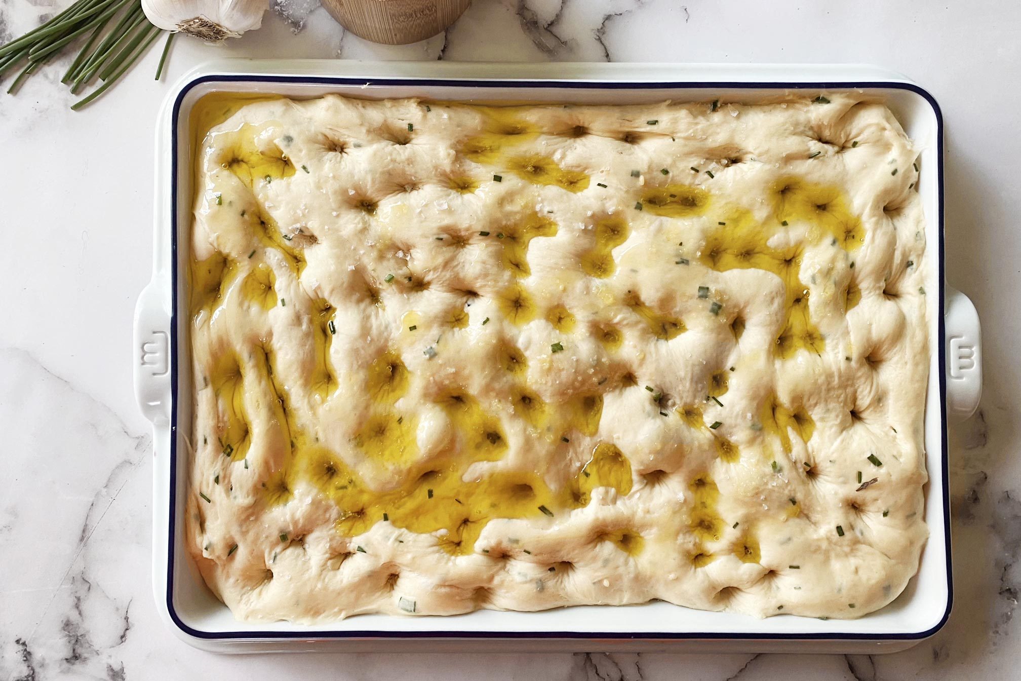 raw focaccia dough in a madeinslab pan on a kitchen counter top