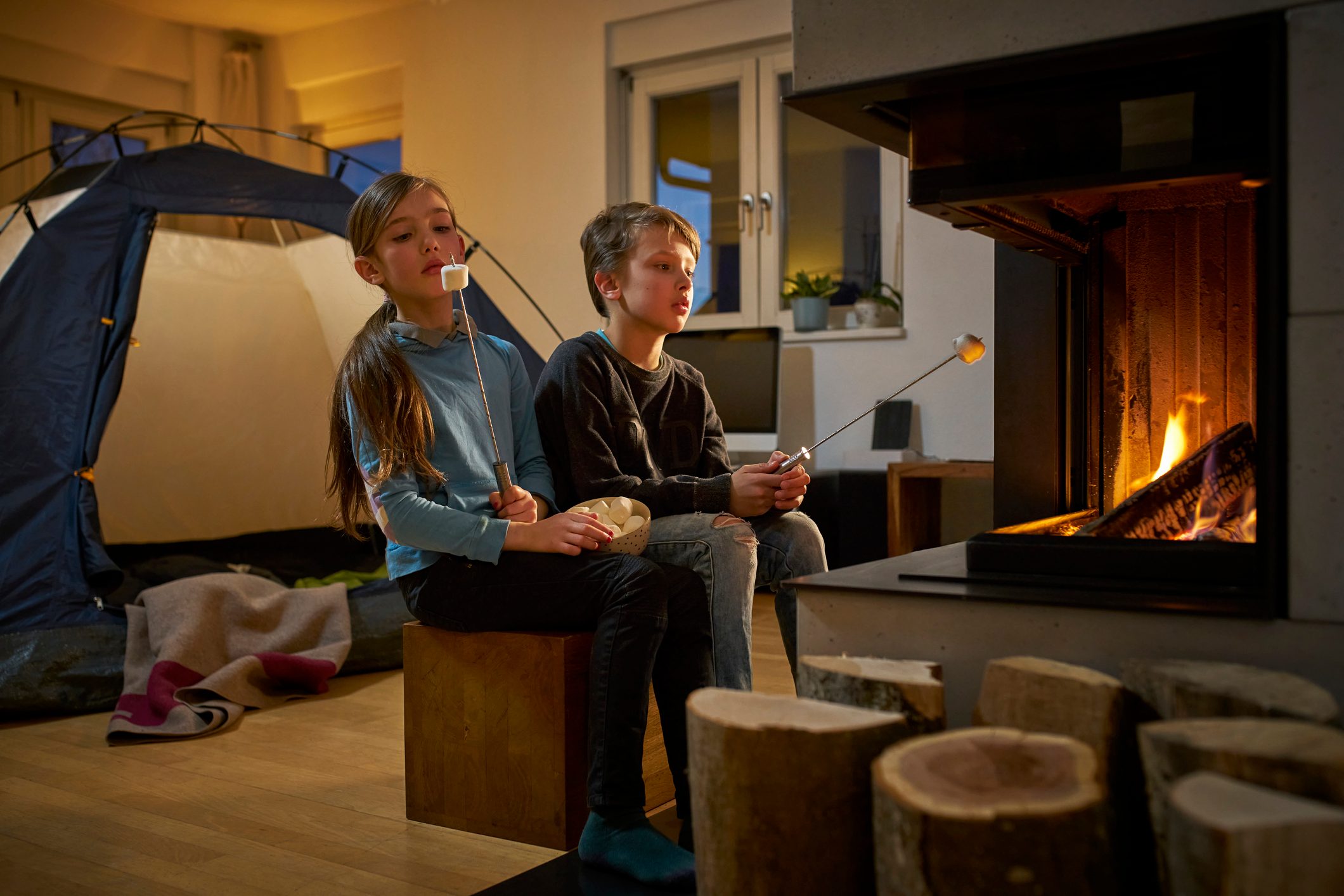 Brother and sister barbecueing and camping in the living room