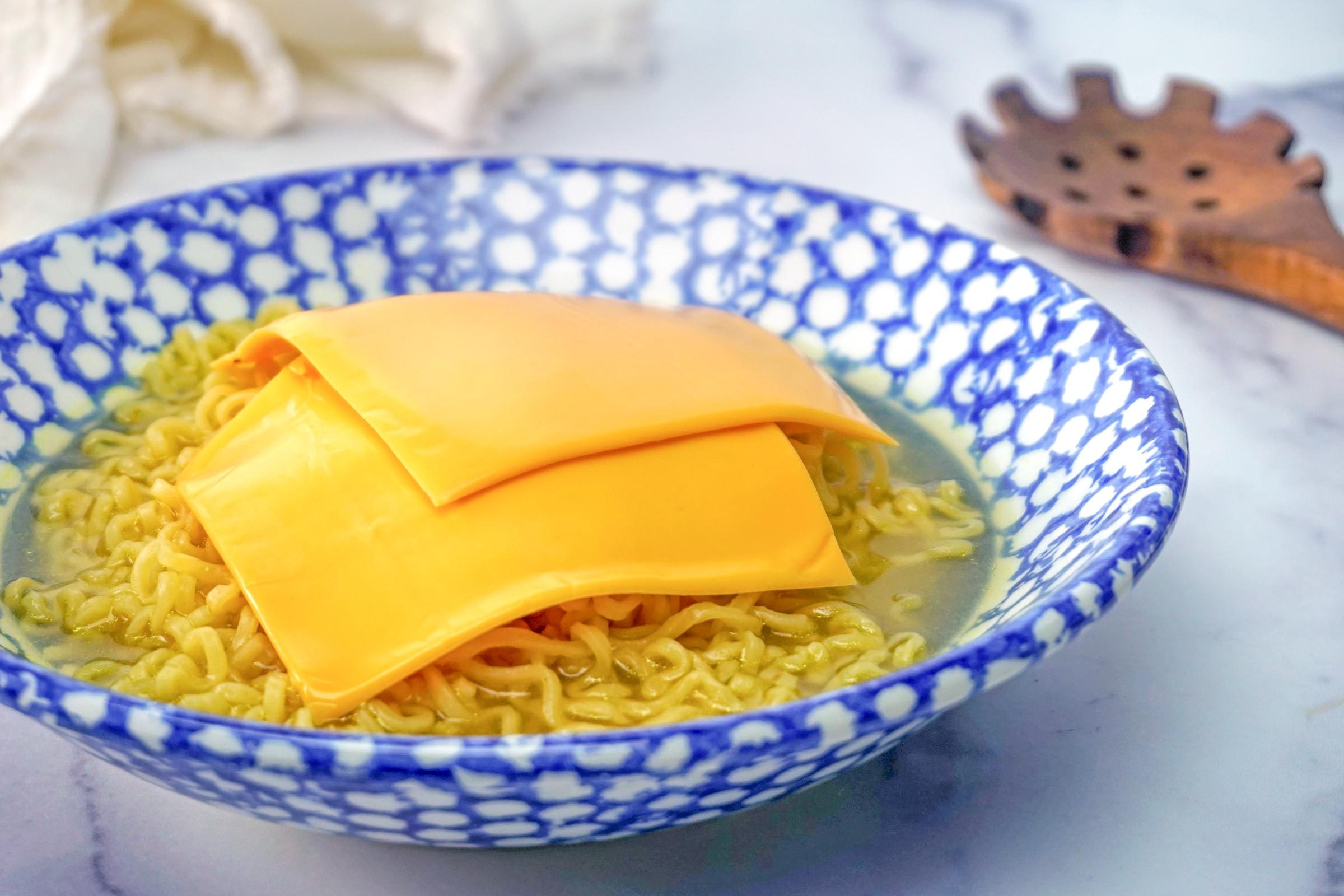 Cheesy Ramen noodles in a bowl with american cheese singles slices on top