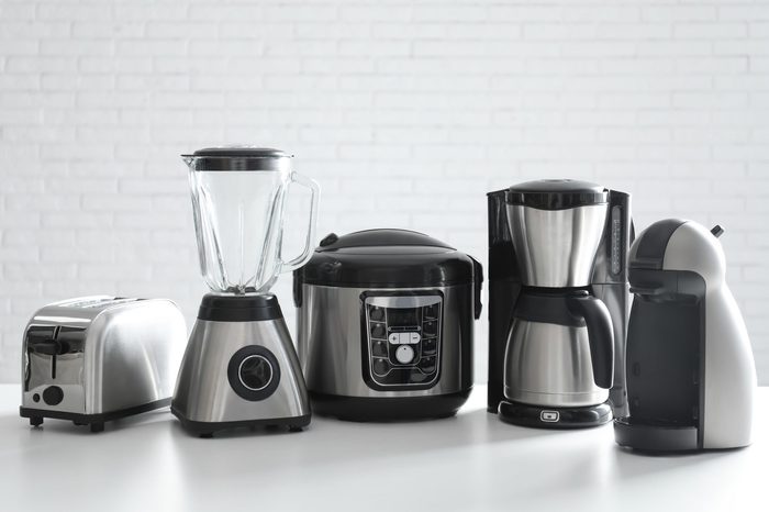 Set of modern home appliances on white table