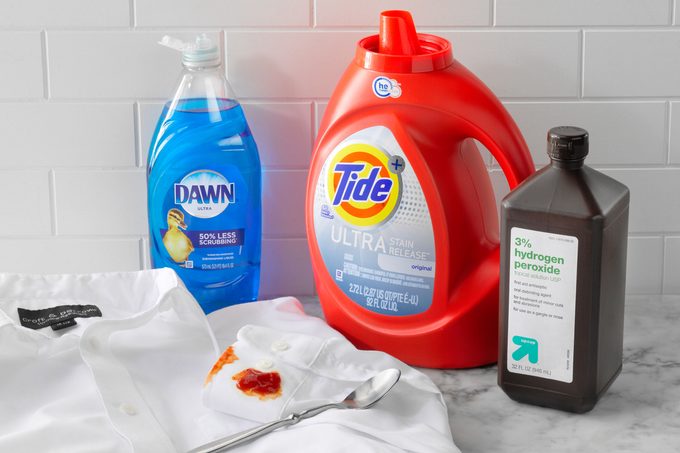 White ketchup stained Shirt Stain With Dawn, Tide, Hydrogen Peroxide and a spoon on marble kitchen counter top