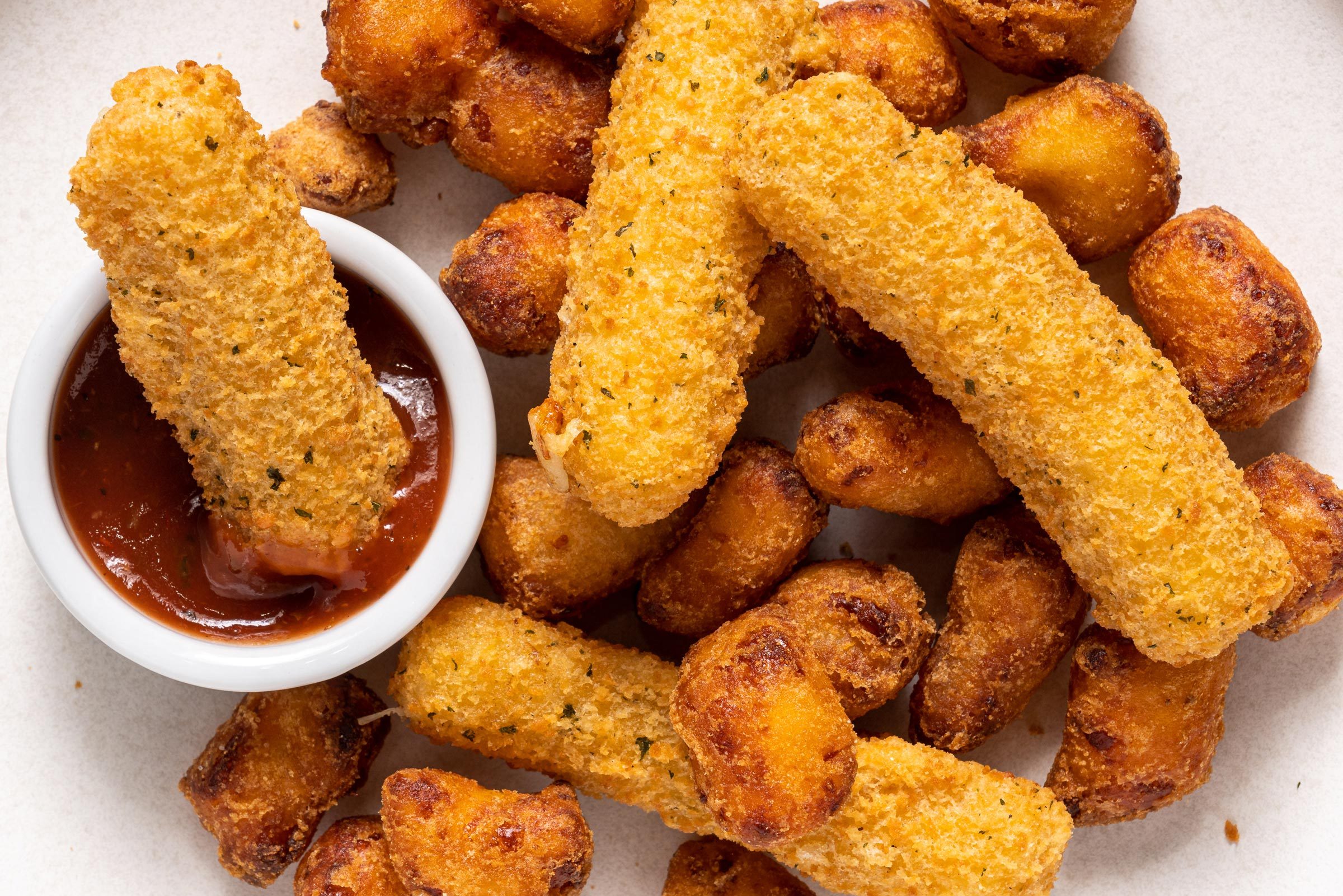 full frame of various mozzarella sticks and dipping sauce