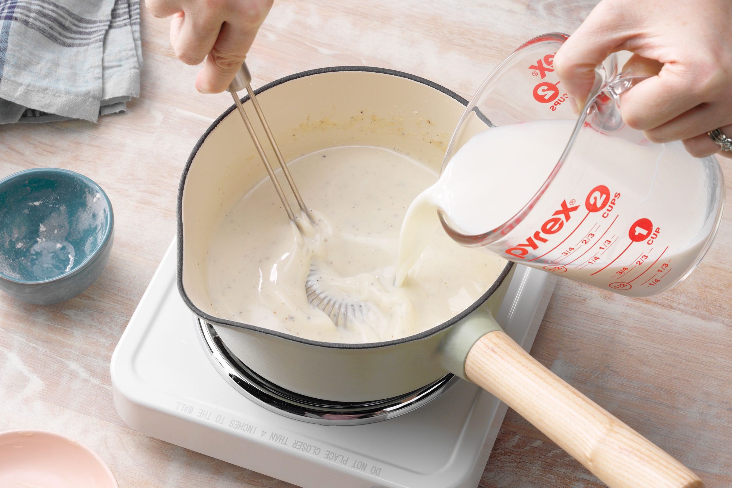 Milk Being Gradually Whisked Into Butter, Flour, Salt And Pepper