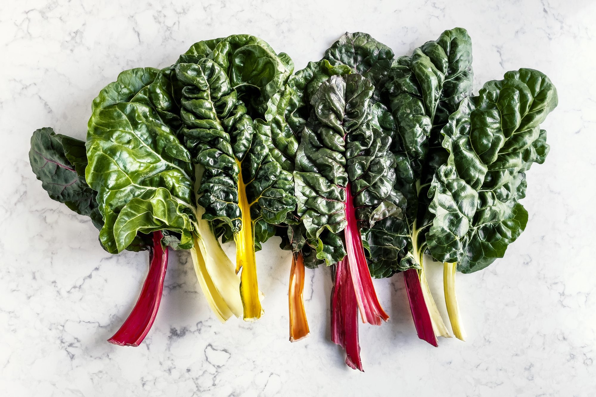 Leaves of Swiss chard on white, marble background