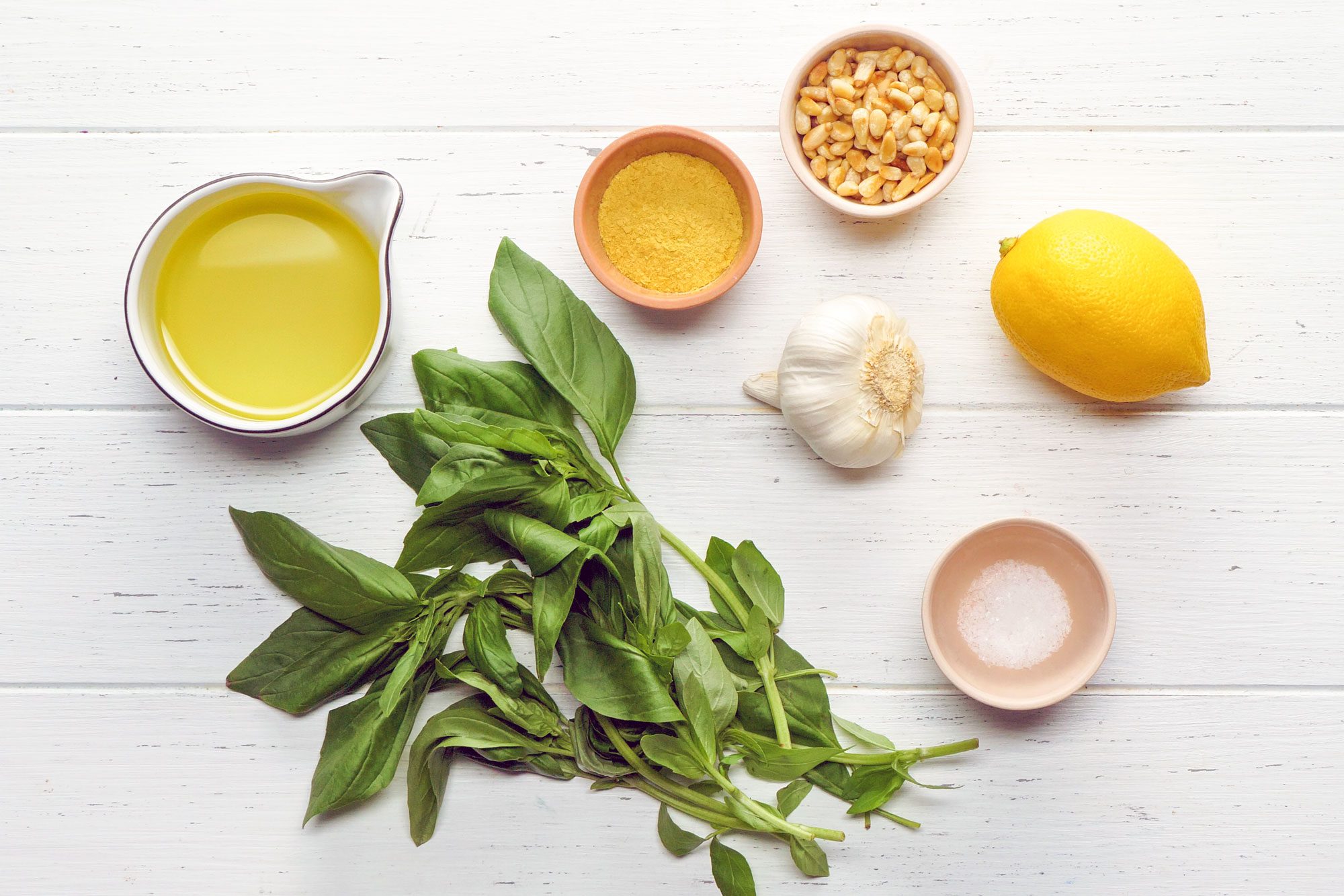 Vegan Pesto ingredients laid out on a white wood surface