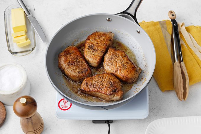 pork chops frying in a pan