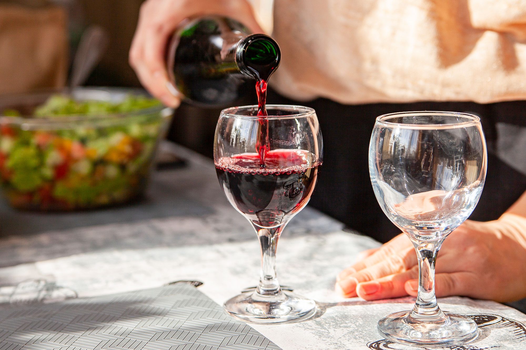 Anonymous Female Pouring Red Wine From Bottle Into Wineglass