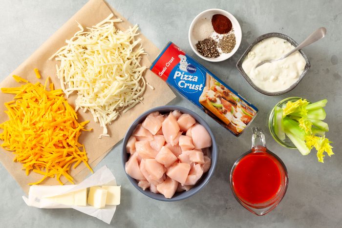 Pizza dough Buffalo wing sauce, chicken and other ingredients placed on a table